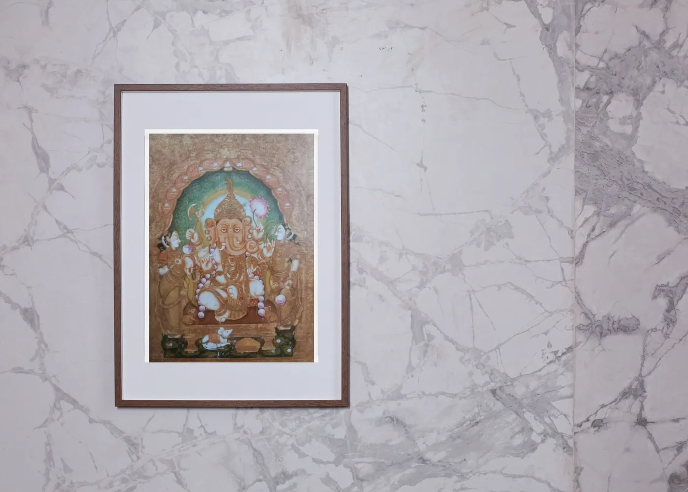 Tanjore Ganesh painting in a wooden frame on a white marble wall